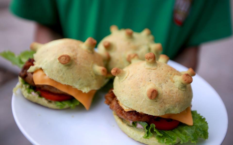 A man holds up coronavirus-themed burgers at a pizza restaurant in Hanoi, Vietnam - SHUTTERSTOCK