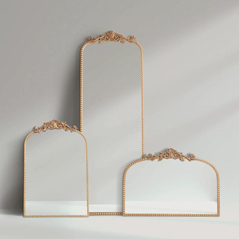 Filigree arched wall mirror decoration made of metal in gold.