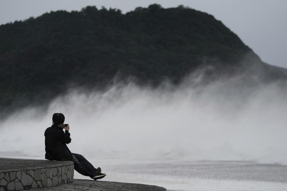 A woman films surging waves as Typhoon Hagibis approaches at a beach in Kumano, Mie prefecture, central Japan Saturday, Oct. 12, 2019. A heavy downpour and strong winds pounded Tokyo and surrounding areas on Saturday as a powerful typhoon forecast as the worst in six decades approached landfall, with streets and train stations deserted and shops shuttered. (AP Photo/Toru Hanai)