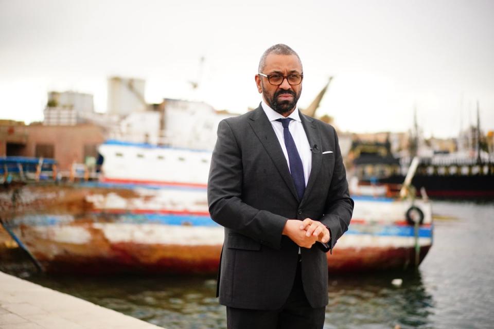 Home Secretary James Cleverly standing in front of a discarded migrant boat in Lampedusa Port, April 2024 (PA)