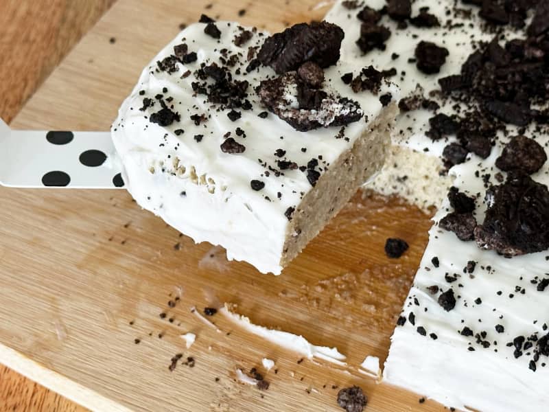 Oreo cake on cutting board with cut piece on black and white poka dot spatula