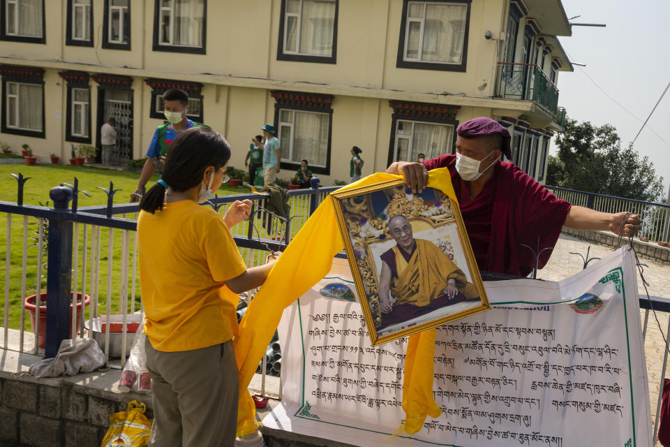 An exile Tibetan monk removes a portrait of his spiritual leader the Dalai Lama as he celebrates the 86th birthday of the Tibetan leader in Dharmsala, India, Tuesday, July 6, 2021. The Dalai Lama made the hillside town of Dharmsala his headquarters after a failed uprising against Chinese rule in 1959.(AP Photo/Ashwini Bhatia)
