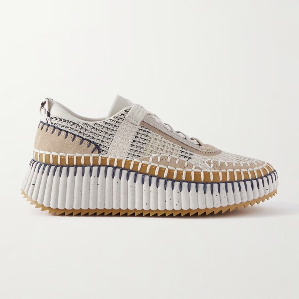 A knit sneaker with white, beige, and brown panels and white and purple contrast stitching