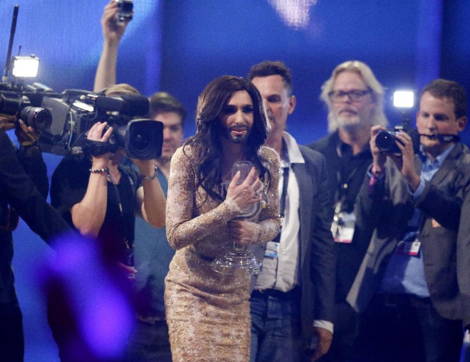 Singer Conchita Wurst representing Austria who performed the song 'Rise Like a Phoenix' hugs the trophy as she is surrounded by media after winning the Eurovision Song Contest in the B&W Halls in Copenhagen, Denmark, Saturday, May 10, 2014.(AP Photo/Frank Augstein)