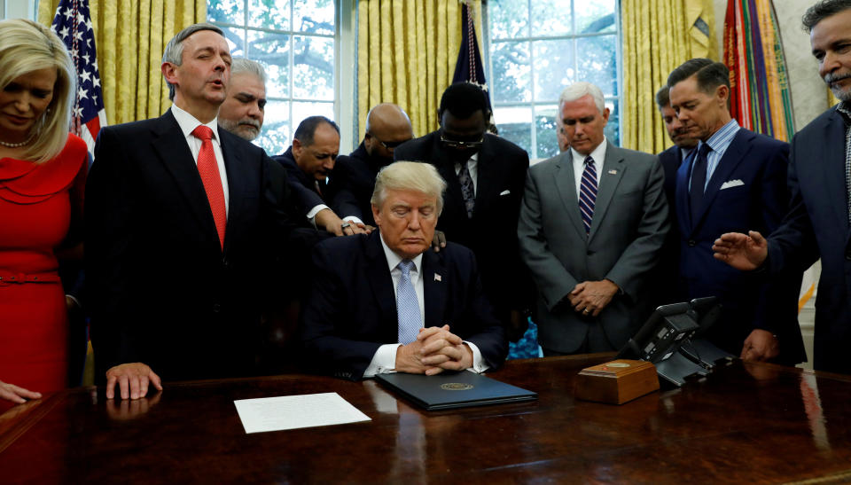 Faith leaders place their hands on the shoulders of President Donald Trump as he takes part in a prayer for those affected by Hurricane Harvey in the Oval Office on Sept. 1, 2017. (Photo: Kevin Lamarque / Reuters)