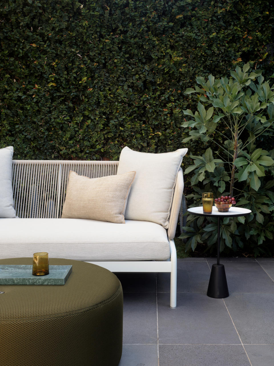 Close-up of white sofa with black side table and olive green ottoman