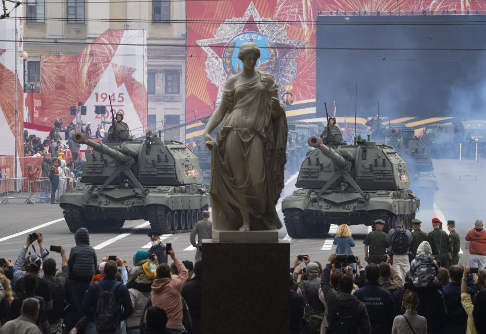 People take photos as self-propelled artillery vehicles Msta-S travel during a rehearsal for a military parade at Dvortsovaya (Palace) Square in St.Petersburg, Russia, Saturday, June 20, 2020. The military parade marking the 75th anniversary of the Nazi defeat was postponed from May 9 due to the outbreak of the coronavirus pandemic and is now set to take place on June 24.(AP Photo/Dmitri Lovetsky)