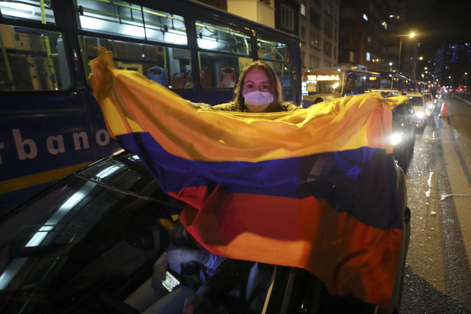 A supporter of former President Alvaro Uribe holds a national flag as she protests the Supreme Court decision to place Uribe under house arrest while it advances a witness tampering investigation against him, in Bogota, Colombia, Tuesday, Aug. 4, 2020. (AP Photo/Fernando Vergara)