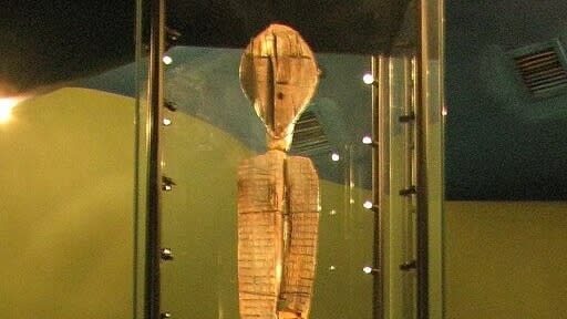  A tall carved statue in a museum. 