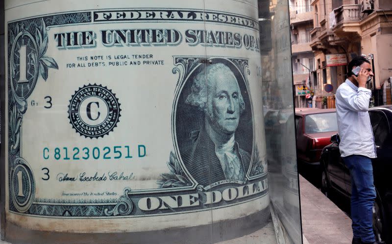 A man talks on his mobile phone in front of a currency exchange bureau advertisement showing images of the U.S. dollar in Cairo