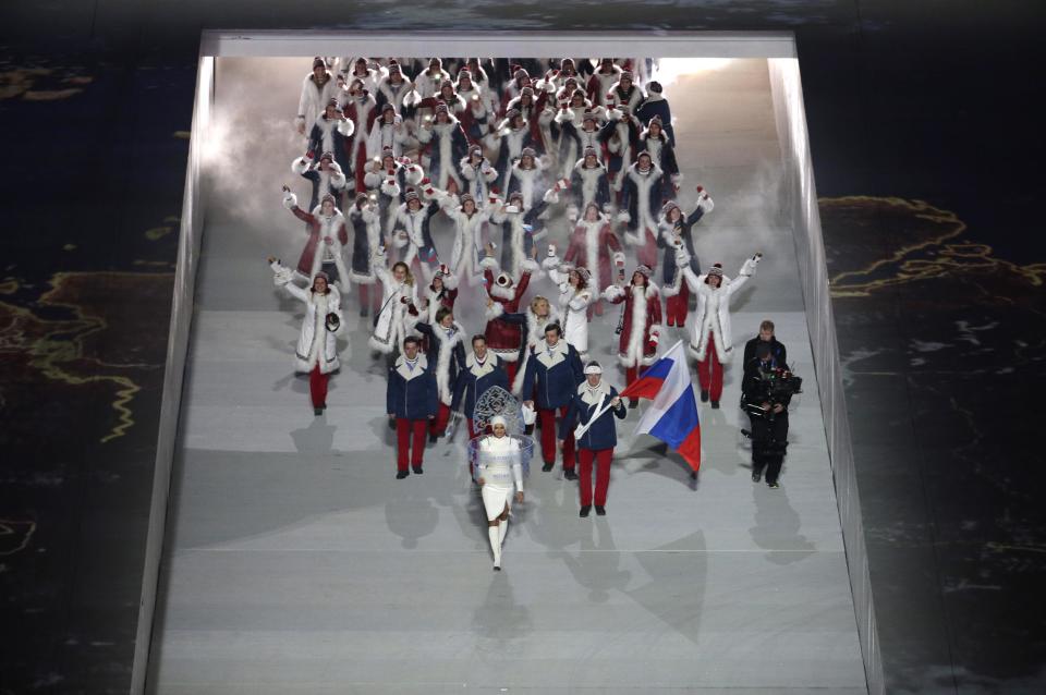 Alexander Zubkov of Russia holds his national flag and enters the arena with teammates during the opening ceremony of the 2014 Winter Olympics in Sochi, Russia, Friday, Feb. 7, 2014. (AP Photo/Charlie Riedel)