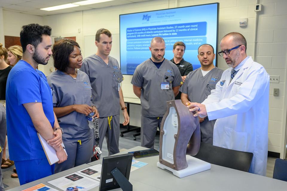 Travis Layne, Middle Tennessee State University director of didactic education, far right, demonstrates a technique on a medical mannequin to students during the grand opening event for the university’s new Physician Assistant Studies graduate program at the Cason Kennedy Nursing Building on campus on May 13, 2022.