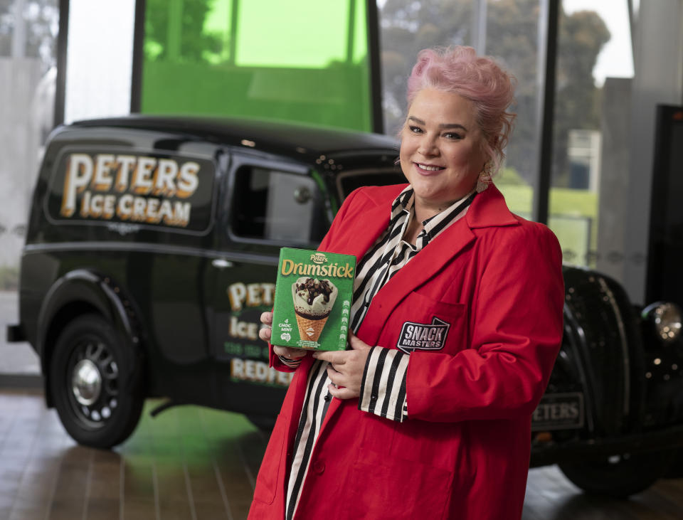 Gogglebox star Yvie Jones in a red coat holding a box of mini Drumstick ice creams in a scene from Snackmasters