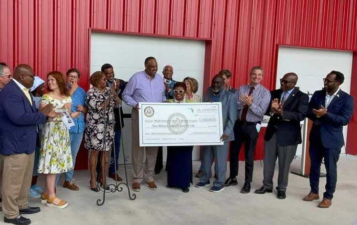 U.S. Rep. Al Lawson (left) presents Ju'Coby Pittman, CEO of Clara White Mission (center) and a City Council member, the symbolic oversized version of a $2 million federal grant to expand the mission's White Harvest Farms. At right of Pittman is Councilmember Sam Newby, who lead earlier efforts to get city funding for the project as well.