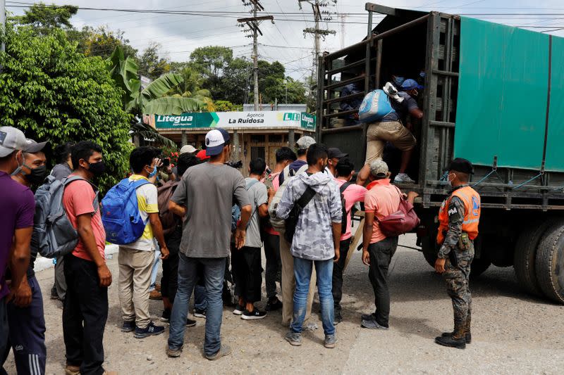 Honduran migrants trying to reach the U.S. get inside a truck escorted by the Guatemalan soldiers to send them back to Honduras, in Morales