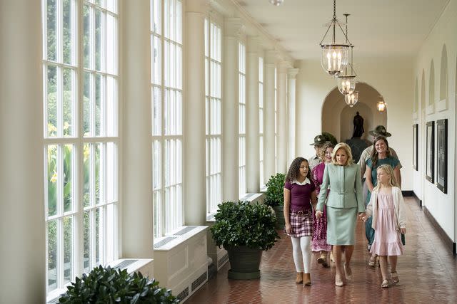 <p>Official White House Photographer Erin Scott</p> First lady Jill Biden walks along the East Colonnade of the White House with two children whose art is displayed in the new military family exhibit