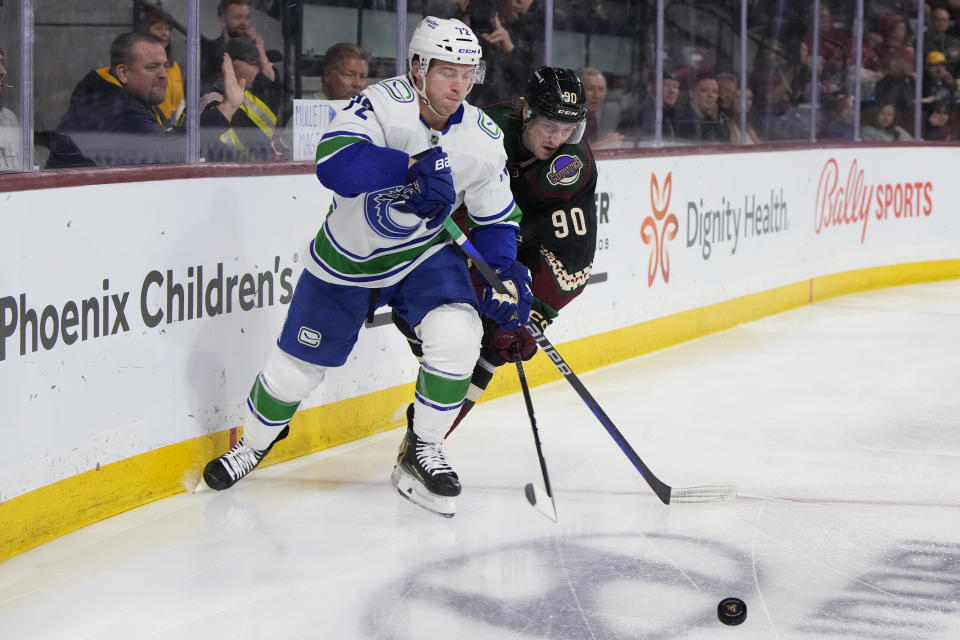 Vancouver Canucks left wing Anthony Beauvillier shields Arizona Coyotes defenseman J.J. Moser (90) from the puck during the second period during an NHL hockey game Thursday, April 13, 2023, in Tempe, Ariz. (AP Photo/Rick Scuteri)