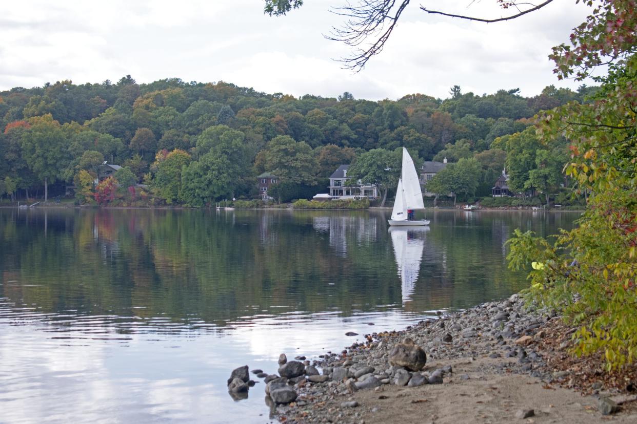 A light breeze sends ripples to the calm waters of Mystic Lake in Arlington, Massachusetts with reflecting white cumulus clouds on the lake's waters.