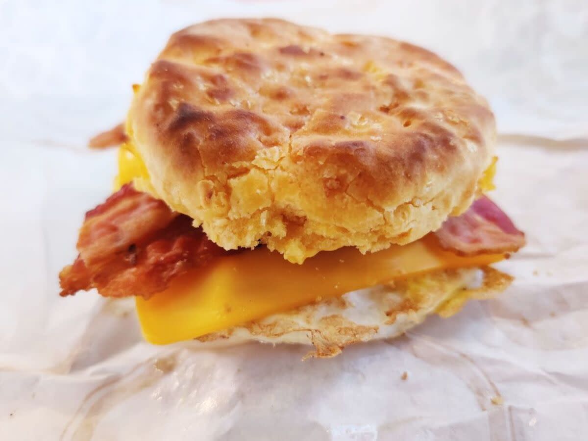 Closeup of Jack in the Box's Cheddar Biscuit Sandwich with Bacon, on white serving paper