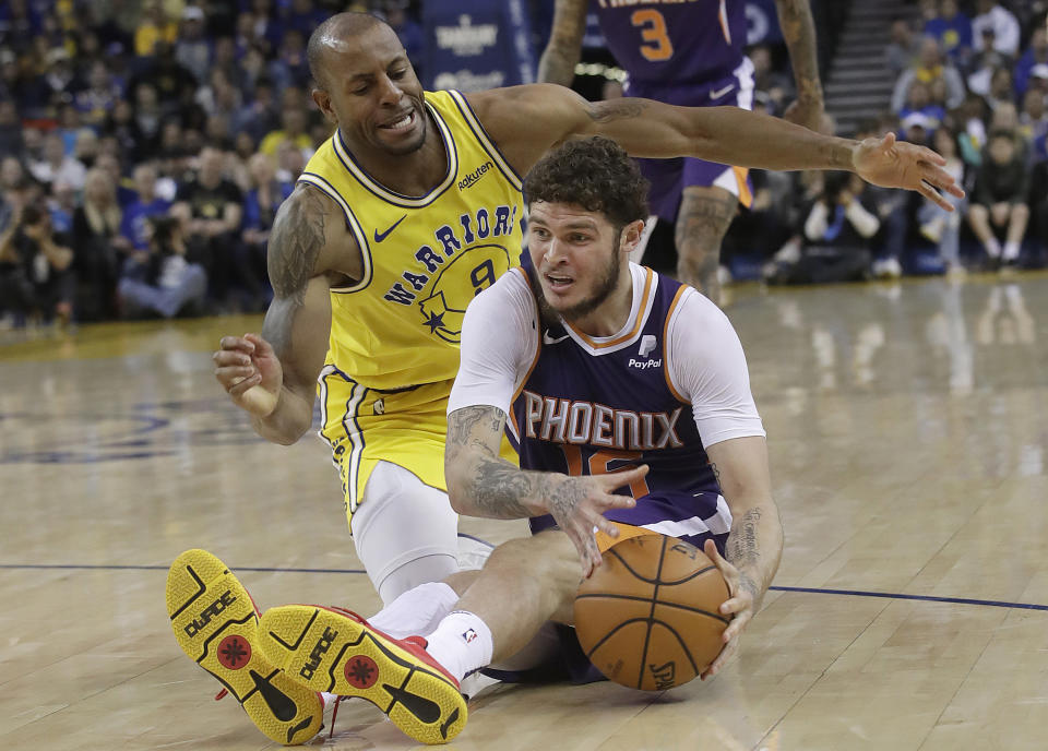 Phoenix Suns guard Tyler Johnson, right, tries to control the ball on the floor as he is guarded by Golden State Warriors guard Andre Iguodala during the second half of an NBA basketball game in Oakland, Calif., Sunday, March 10, 2019. (AP Photo/Jeff Chiu)