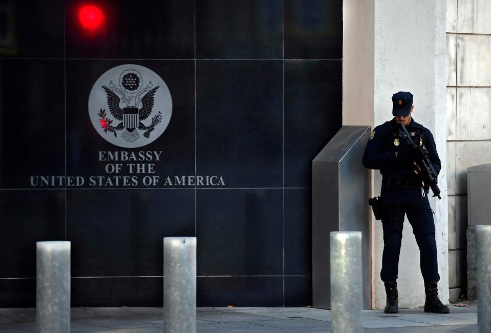 A policeman stands guard near the U.S. embassy in Madrid, on Dec. 1. The U.S. Travel Association estimates that visa wait times will cost the U.S. economy $7 billion in 2023.