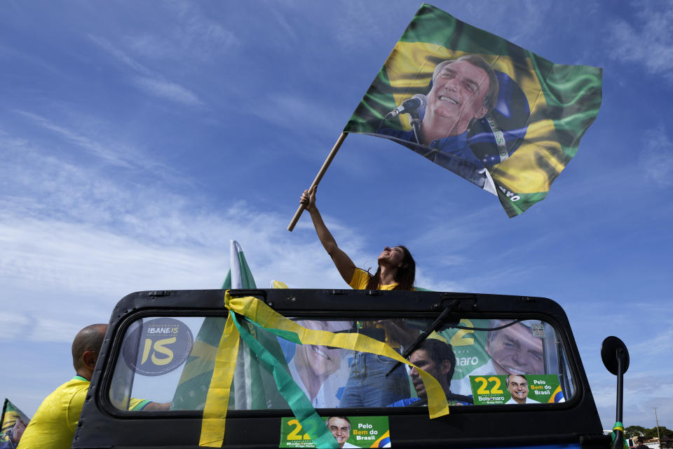 A woman waves a banner with an image of Brazil's President Jair Bolsonaro during a campaign event in Brasilia, Brazil, Saturday, Oct. 29, 2022. Bolsonaro is facing former President Luiz Inacio Lula da Silva in a runoff election set for Oct. 30. (AP Photo/Eraldo Peres)