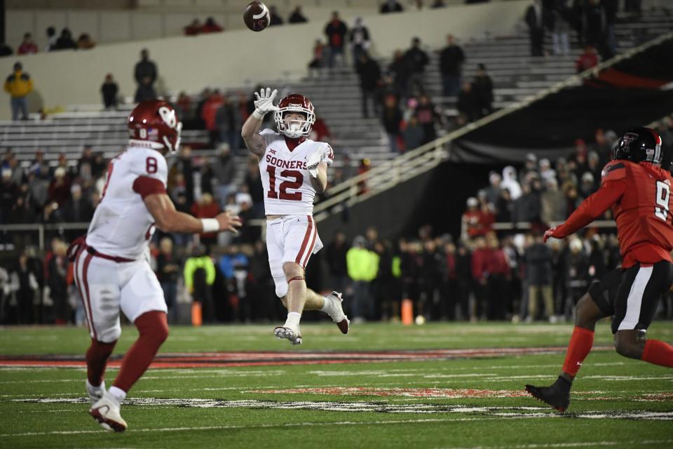 Oklahoma wide receiver Drake Stoops (12) passes the ball to quarterback Dillon Gabriel (8) during overtime of the team's NCAA college football game against Texas Tech on Saturday, Nov. 26, 2022, in Lubbock, Texas. (AP Photo/Justin Rex)