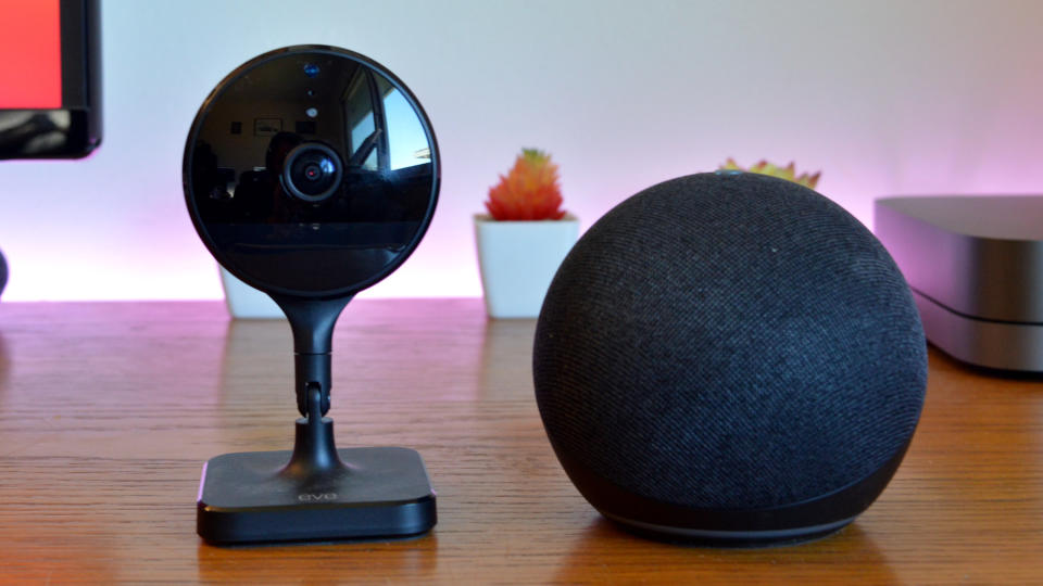 A security camera next to an Amazon Echo Dot on a table