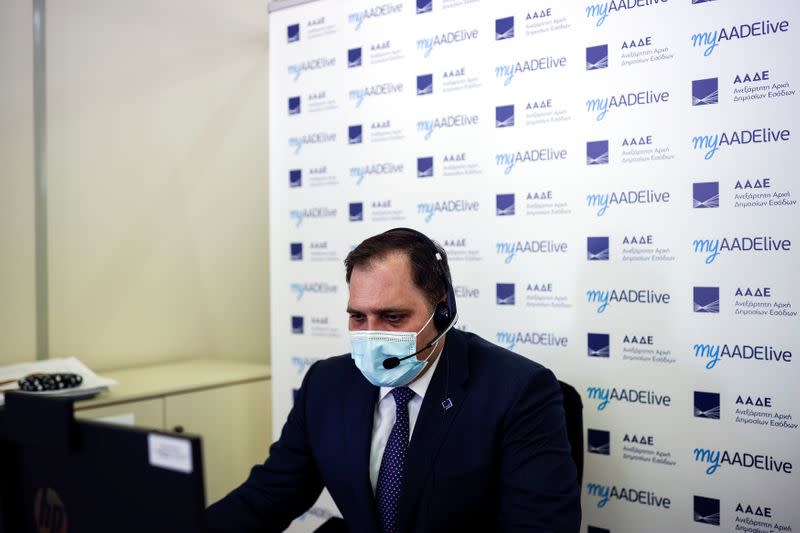 Head of the State Independent Authority of Public Revenue George Pitsilis speaks to a citizen via teleconference in Athens