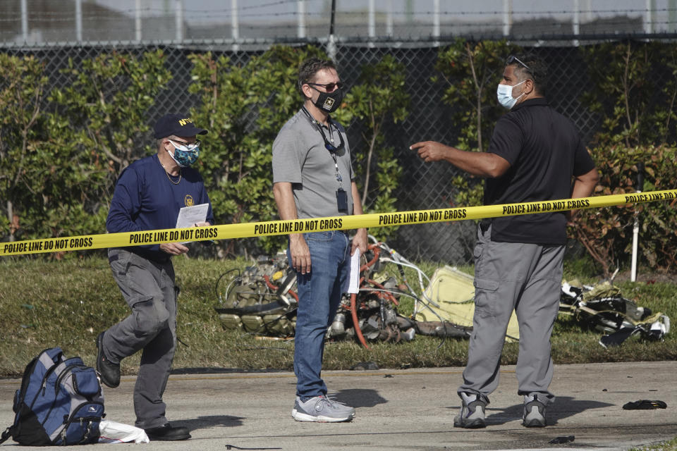 NTSB investigators work the scene of a Monday plane crash near North Perry Airport in Pembroke Pines, Tuesday, March 16, 2021. A four-year-old child riding in a vehicle on the ground and the pilot and passenger in the plane were killed. (Joe Cavaretta/South Florida Sun-Sentinel via AP)