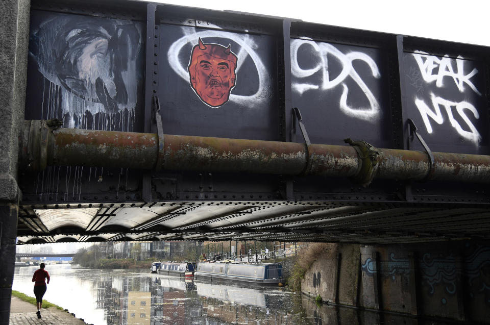 A woman runs along a towpath near graffiti depicting U.S. President Donald Trump on a canal bridge in east London, Britain, February 18, 2017.&nbsp;