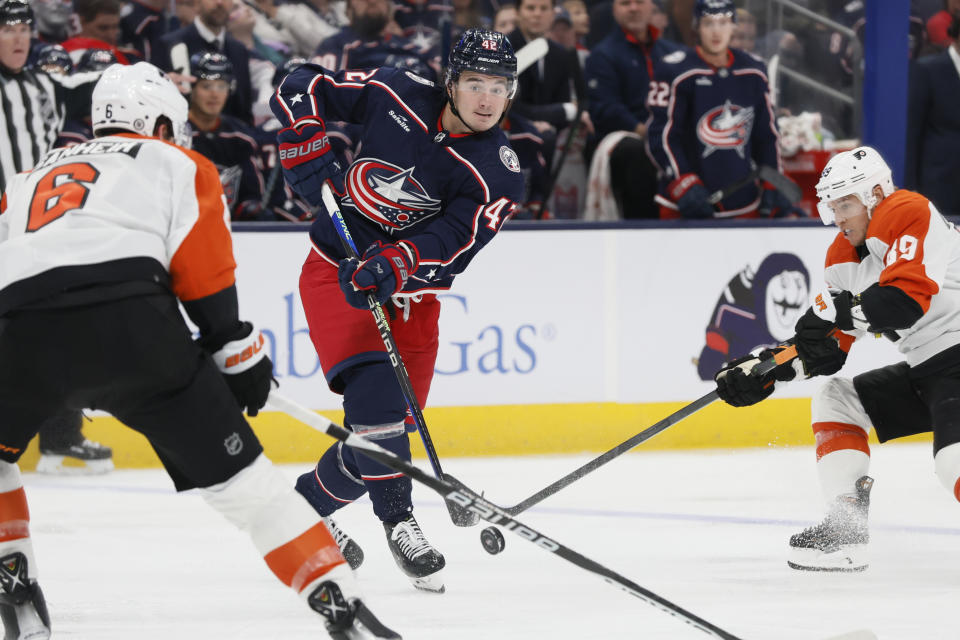 Columbus Blue Jackets' Alexandre Texier, center, passes the puck between Philadelphia Flyers' Travis Sanheim, left, and Cam Atkinson during the second period of an NHL hockey game Thursday, Oct. 12, 2023, in Columbus, Ohio. (AP Photo/Jay LaPrete)