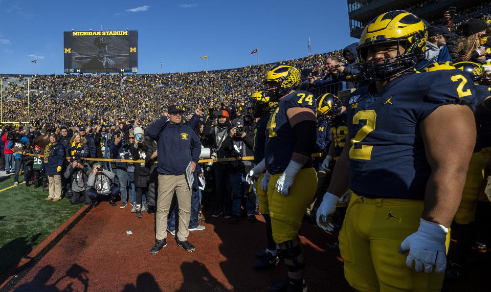 Michigan head coach Jim Harbaugh, center, prepares to lead his team on to the Michigan Stadium field before an NCAA college football game against Michigan State in Ann Arbor, Mich., Saturday, Nov. 16, 2019. (AP Photo/Tony Ding)