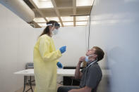 Nurse Esma Radoncic, left, prepares to take a nasal swab from Eric Antosh at a COVID-19 testing site in Brooklyn run by NYC Health + Hospitals as part of the "Get Tested Day of Action," Wednesday, July 8, 2020, in New York. Free testing is being offered at sites throughout the city. (AP Photo/Mark Lennihan)