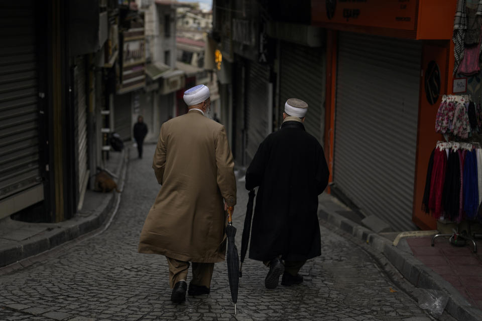 Two Muslim clerics walk along a cobblestone street nearby Sultan Ahmet mosque in Istanbul, Wednesday, March 20, 2024. (AP Photo/Khalil Hamra)