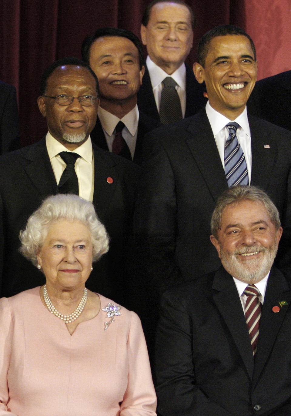 Britain's Queen Elizabeth II, sits with G20 leaders during a group photograph at Buckingham Palace in London, on April 1, 2009. Italian Prime Minister Silvio Berlusconi, seen at top. Berlusconi, the boastful billionaire media mogul who was Italy's longest-serving premier despite scandals over his sex-fueled parties and allegations of corruption, died, Italian media reported Monday. He was 86. (AP Photo/Kirsty Wigglesworth, Pool, File)