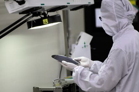 FILE PHOTO: A worker checks a wafer chip in the clean room at the UTAC plant in Singapore