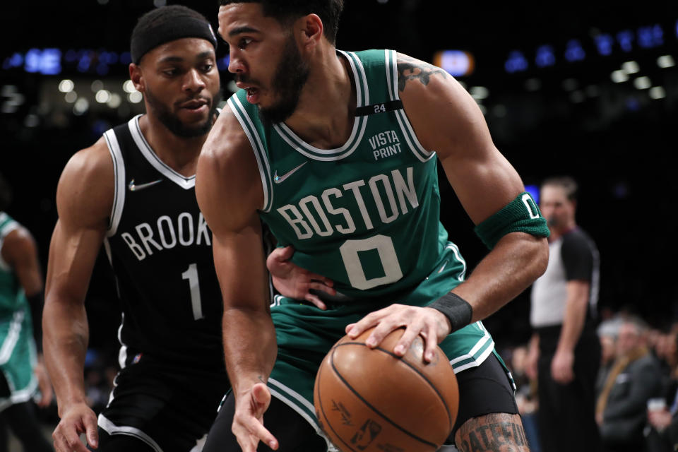 Boston Celtics forward Jayson Tatum (0) is defended by Brooklyn Nets forward Bruce Brown (1) during the first half of an NBA basketball game Thursday, Feb. 24, 2022, in New York. (AP Photo/Noah K. Murray)