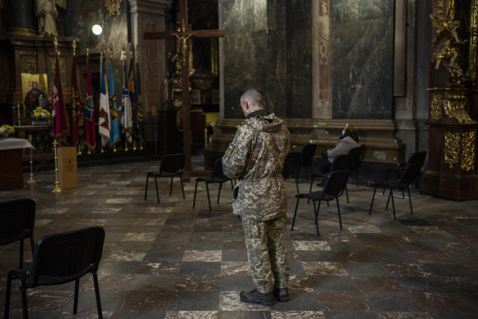 A Ukrainian man dressed in military attire prays inside the Saints Peter and Paul Garrison Church in Lviv, western Ukraine, Sunday, March 6, 2022. (AP Photo/Bernat Armangue)