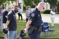 Officer Ben Hubbard, of the Collierville Police Department, prays during a vigil at the Collierville Town Hall, Friday, Sept. 24, 2021, in Collierville, Tenn. The vigil is for the person killed and those injured when a gunman attacked people in a Kroger grocery store Thursday before he was found dead of an apparent self-inflicted gunshot wound. (AP Photo/Mark Humphrey)