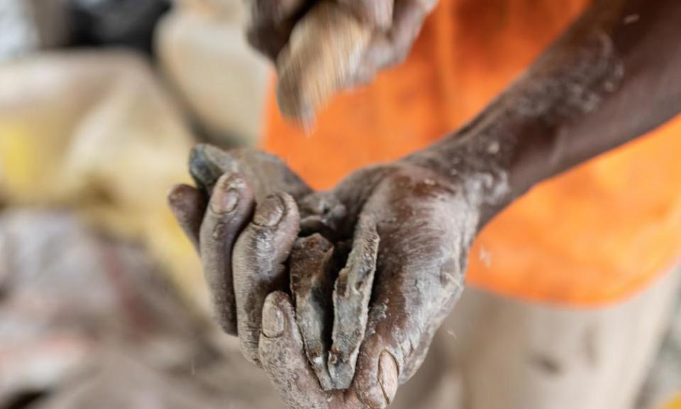 A miner splits open a rock in the hope of finding tiny gold deposits within its layers.