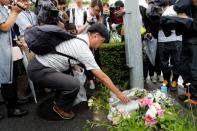 A man placed flowers near the torced Kyoto Animation building to mourn the victims of the arson attack in Kyoto