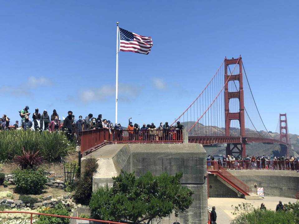 Dozens of people gather by the Golden Gate Bridge Welcome Center in San Francisco Saturday, June 6, 2020, to begin marching across the famous span bridge in support of the Black Lives Matter movement. People are protesting the death of George Floyd, who died after he was restrained by Minneapolis police on May 25 in Minnesota. (AP Photo/Jeff Chiu)
