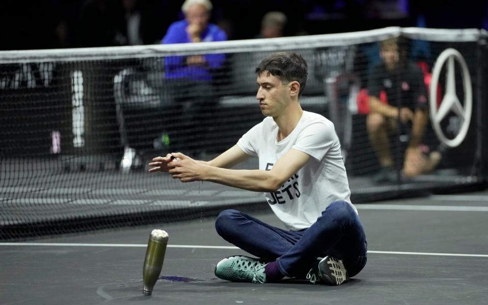 A man pours flammable liquid to sets fire on his hand during protest at a match Team World's Diego Schwartzman against Team Europe's Stefanos Tsitsipas on day one of the Laver Cup tennis tournament at the O2 in London, Friday, Sept. 23, 2022 - AP