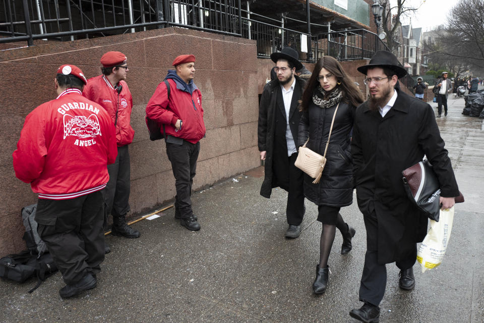 Members of the Guardian Angels, left, a volunteer safety patrol organization, stand in front of the Chabad Lubavitch World Headquarters, Monday, Dec. 30, 2019 in the Brooklyn borough of New York. The Guardian Angels and police have increased patrols in the Crown Heights neighborhood following an anti-Semitic attack on a Hanukkah celebration in Monsey, N.Y. (AP Photo/Mark Lennihan)