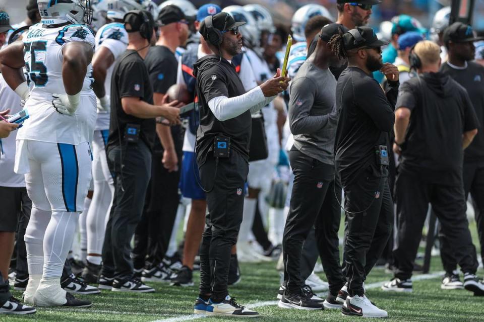 Panthers assistant defensive backs coach DeAngelo Hall, center, holds a sign with a number for the defense during the pre-season game against the Jets at Bank of America Stadium on Saturday, August 12, 2023 in Charlotte, NC.