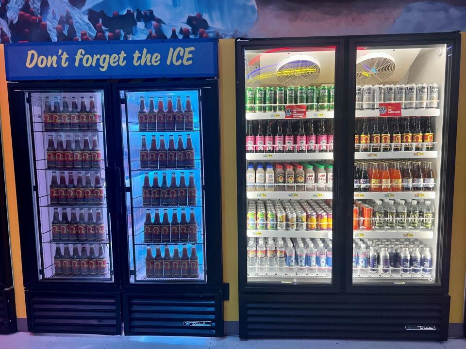 Two refrigerators side by side of drinks. The right side has real, buyable drinks, the left is a fake entrance.