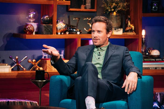 Armie gesturing as he sits on a chair and speaks