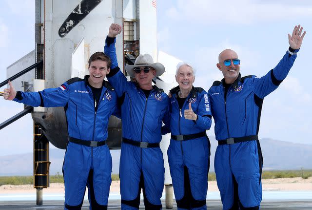 <p>Joe Raedle/Getty</p> Oliver Daemen, Jeff Bezos, Wally Funk and Mark Bezos pose for a picture near the booster after flying into space in the Blue Origin New Shepard rocket on July 20, 2021 in Van Horn, Texas.