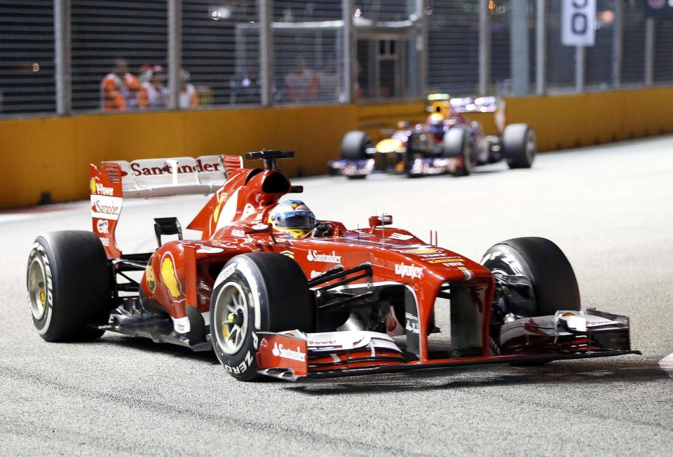 Ferrari Formula One driver Fernando Alonso of Spain races ahead of Red Bull Formula One driver Mark Webber of Australia during the Singapore F1 Grand Prix at the Marina Bay street circuit in Singapore September 22, 2013. REUTERS/Natashia Lee (SINGAPORE - Tags: SPORT MOTORSPORT F1)